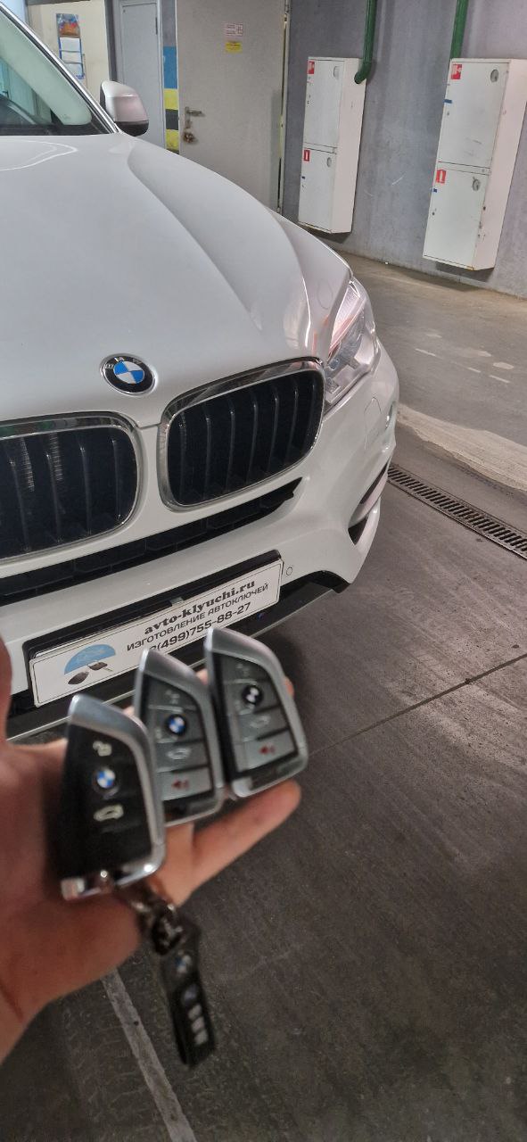 Готовые ключи для BMW X5 в руке мастера у автомобиля клиента