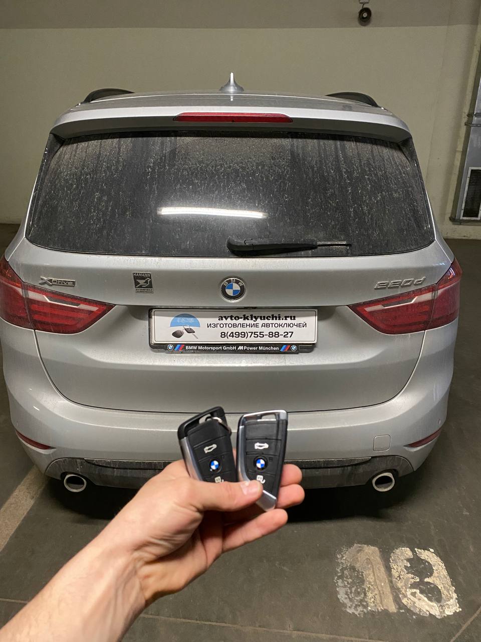 Готовые ключи для BMW 220d Gran Tourer в руке мастера у автомобиля клиента